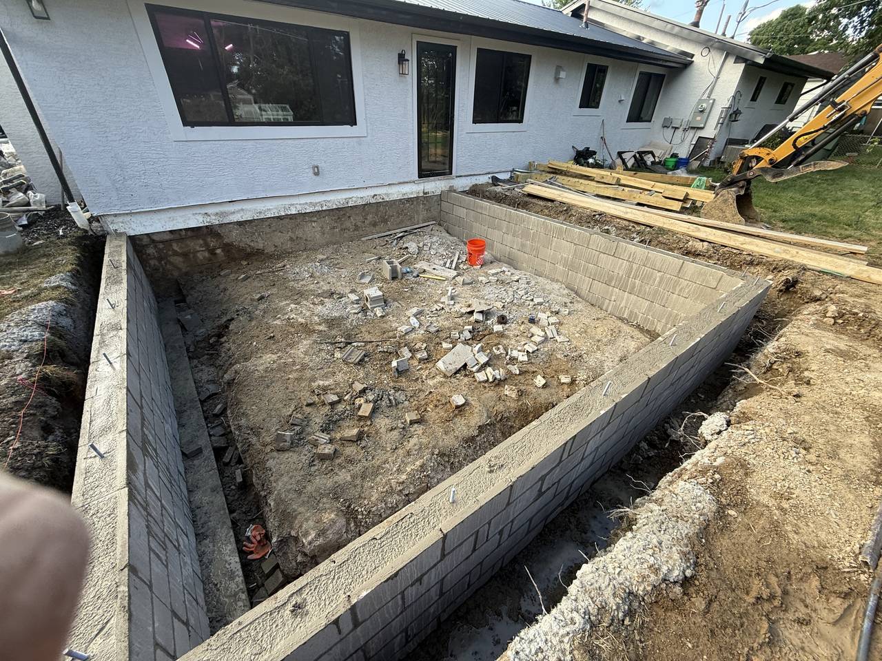 CMU block foundation walls for a home addition with excavation equipment on site