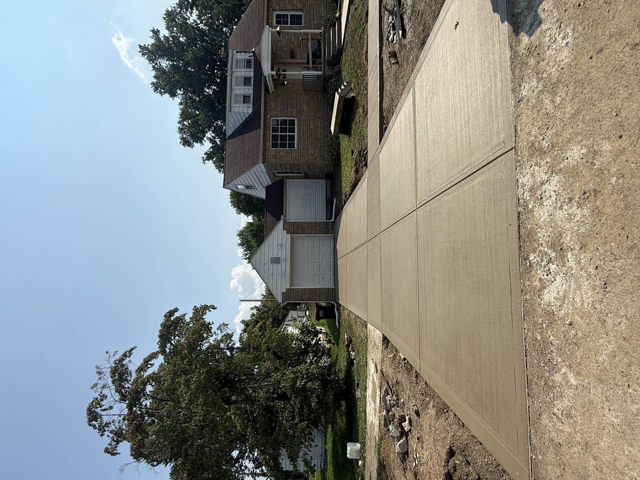 Broom-finish concrete driveway leading to a detached garage