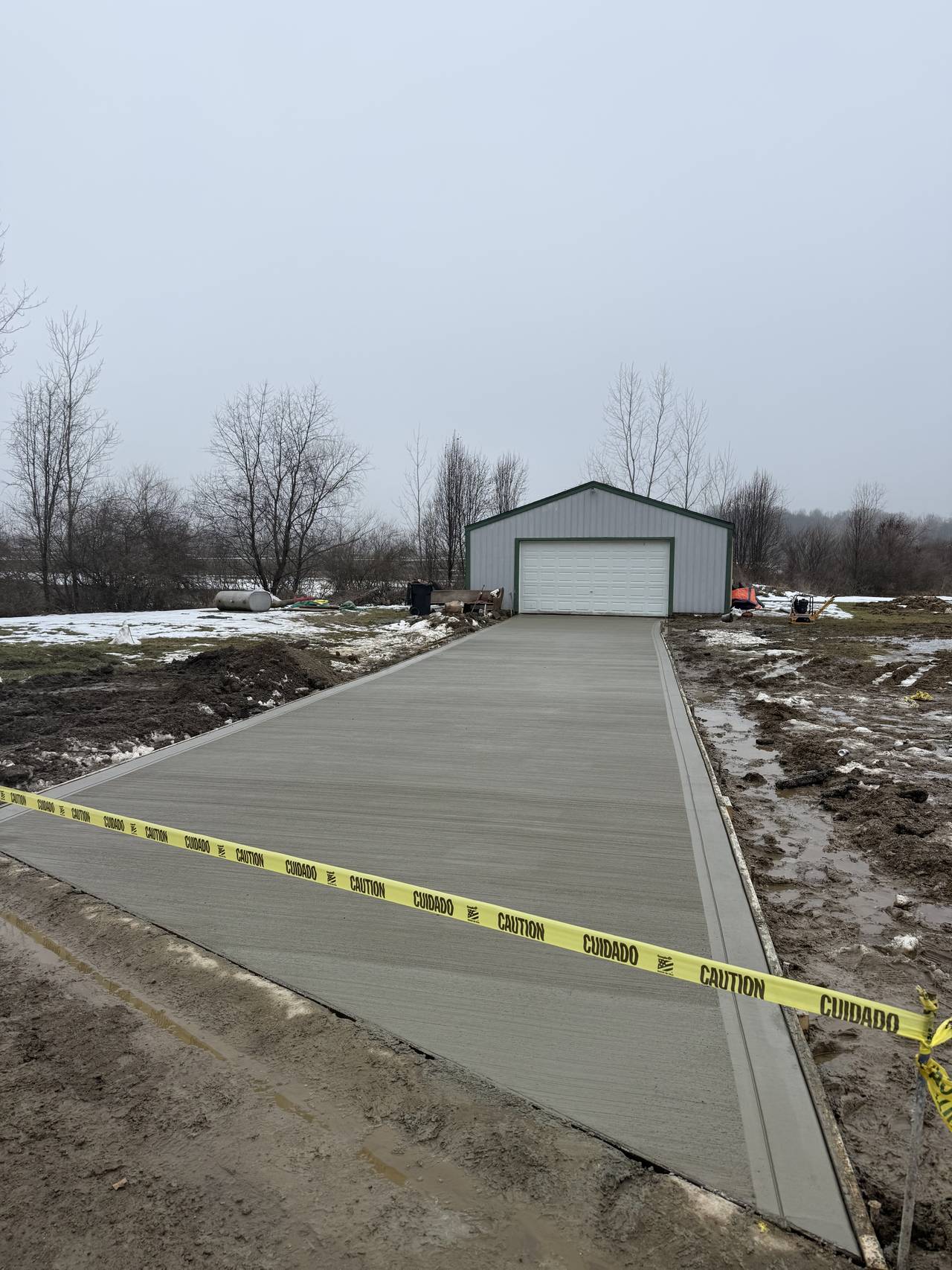 Concrete driveway leading to a metal pole barn garage