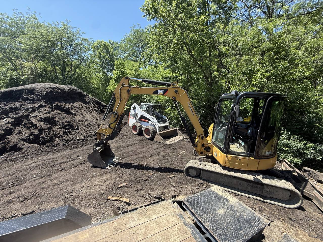 Excavator and skid steer working an earthwork site