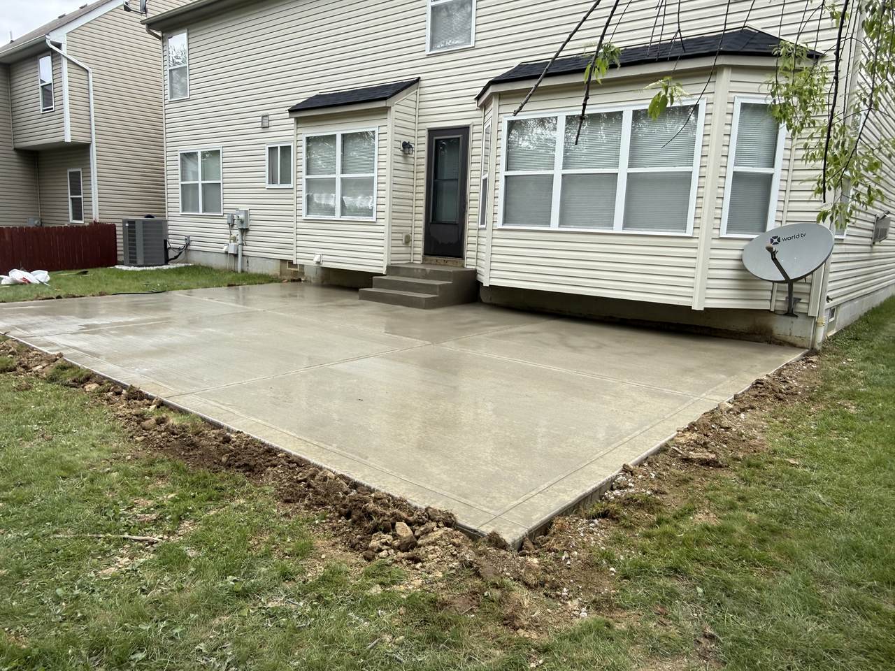 Concrete patio with steps leading to a sunroom addition