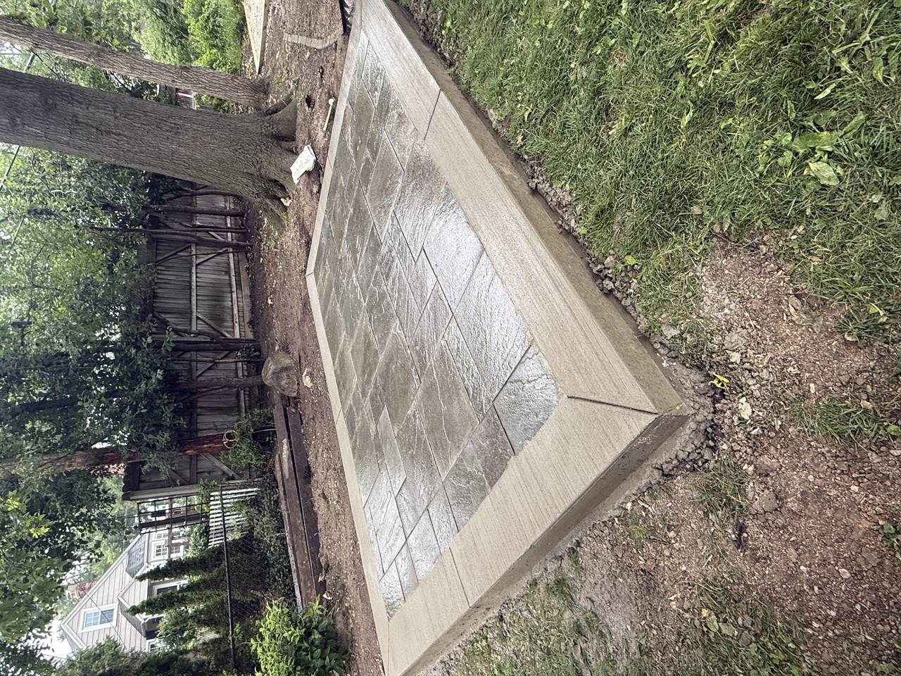 Stamped ashlar-pattern concrete patio in a shaded backyard